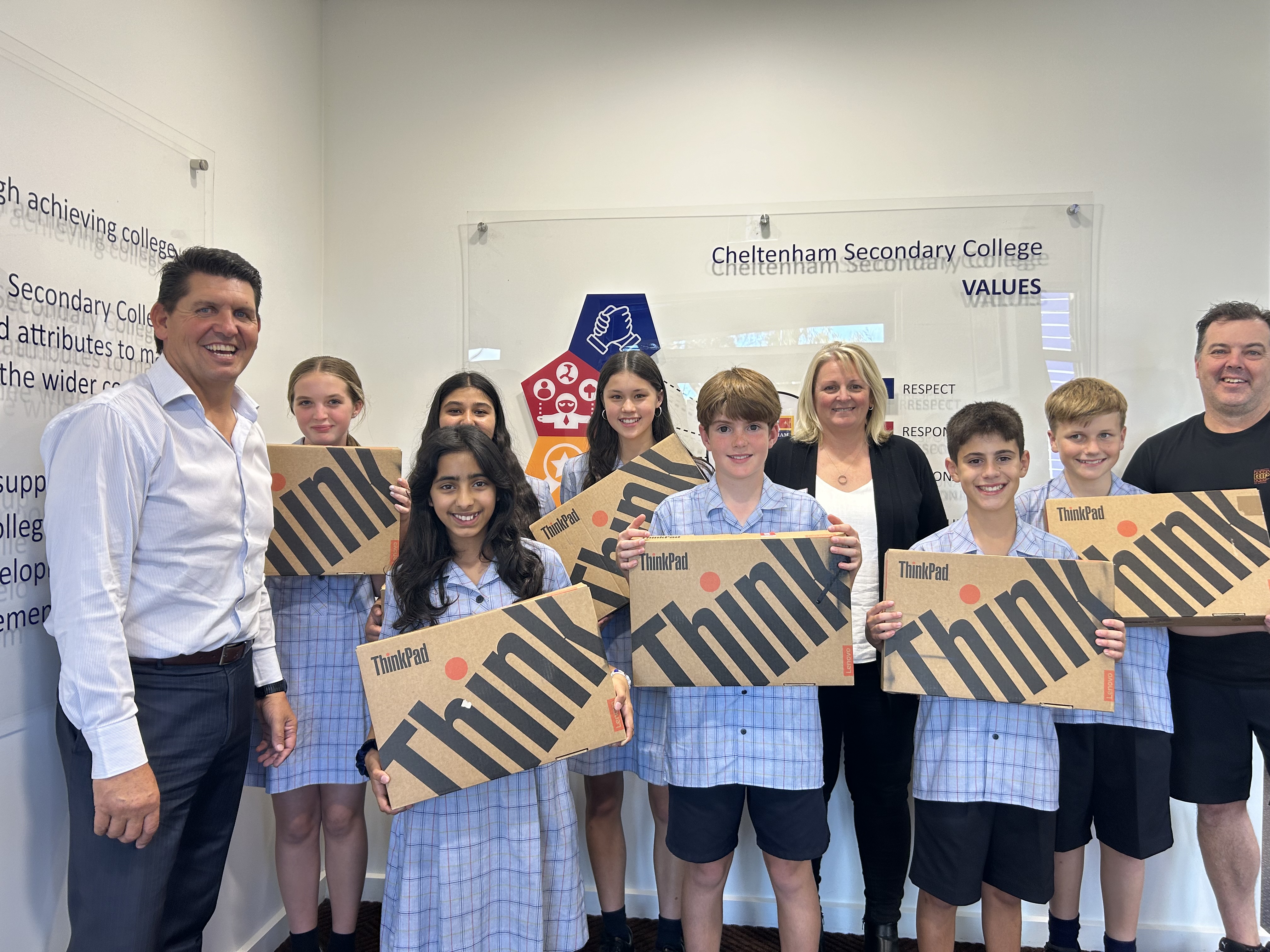Students holding their new laptops at a partner school